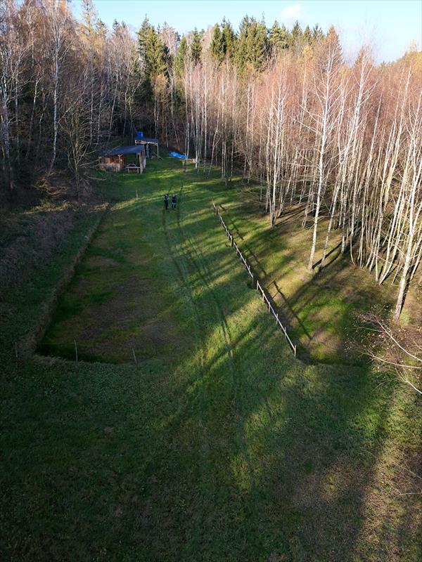 Celkový pohled na hlavní louku. Po stranách jsou vyrovnané plochy na stany, v pozadí kuchyně a kontejner. 